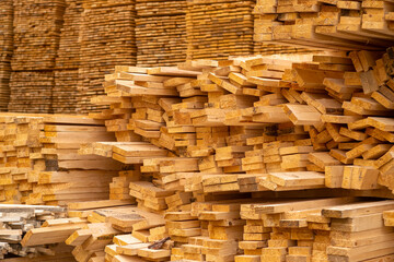 Wooden boards are stored outdoors. Wooden boards, lumber, industrial wood, timber. Pine wood timber stack of natural rough wooden boards on building site.