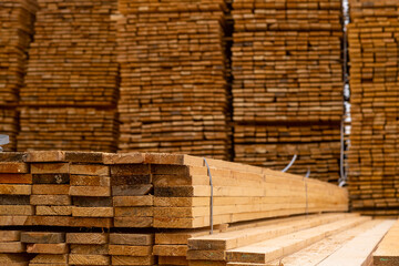 Wooden boards are stored outdoors. Wooden boards, lumber, industrial wood, timber. Pine wood timber stack of natural rough wooden boards on building site.