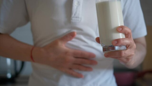 Lactose intolerance. A woman with a glass of milk holds his stomach feeling discomfort