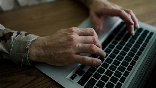 Hands of a male military in uniform typing notes. Laptop work