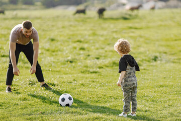 Father and son playing with a ball on summer outdoors