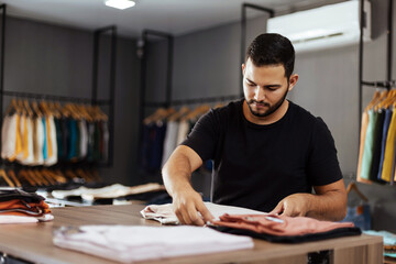 Small business. Men's clothing and accessories store. Owner organizing the products.