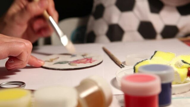 Paint handmade Beverage coasters. Mother with little son making a home artwork. Teaching and family values concept video.