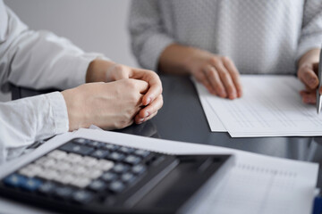 Woman accountant using a calculator and laptop computer while counting taxes for a client. Business...