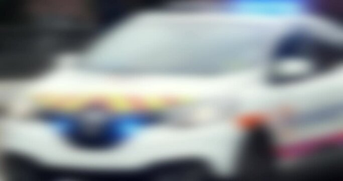 A police car, its beacons aglow in the bright French day, drives down a blurred street view.