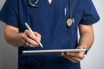 doctor in uniform with a stethoscope enters a prescription into a tablet computer.