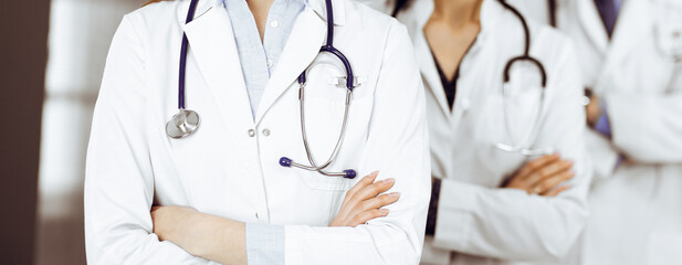 Group of professional doctors is standing as a team with arms crossed in clinic. Medicine concept during Coronavirus pandemic