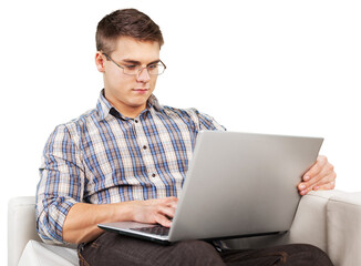 A handsome young man in glasses using a laptop on the sofa