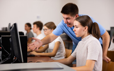 Fototapeta premium Boy and girl student emotionally reacting while studying at computer in college technology class