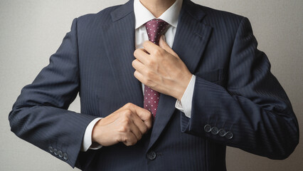 ネクタイを締めて身だしなみを整えるビジネスマン