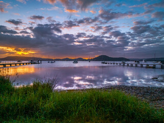 Aerial sunrise over the water with low cloud cover, boats and reflections