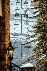 wintry mountain resort, snow-covered slopes, mechanized ski lift, skiers and snowboarders ascending, steel cables and poles, panoramic view of snowy peaks