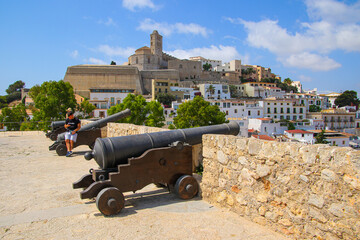 Fototapeta na wymiar Canons on the terrace of a bastion offering a view on Dalt Vila, the old city center of Ibiza in the Balearic Islands, Spain - Medieval fortress with whitewashed houses in the Mediterranean Sea