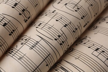 Rolled sheets with music notes as background, closeup