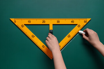 Woman drawing with chalk and triangle ruler on green board, closeup