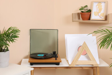 Stylish turntable with vinyl record on wooden table in cozy room