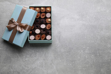 Open box of delicious chocolate candies on light grey table, top view, Space for text