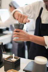 Barista coffee dripper and pour over filter with ground coffee in the funnel. Working in restaurant and cup with brewing process. Coffee shop concept.