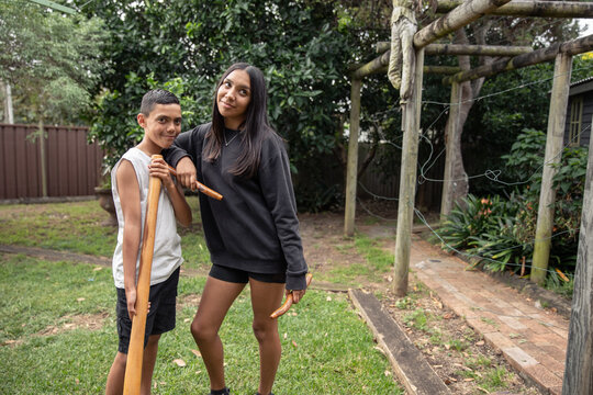 First Nations teenagers holding Indigenous instruments