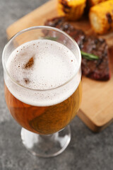 Glass of tasty beer on grey table, closeup