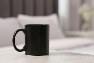 Black ceramic mug on table indoors. Mockup for design