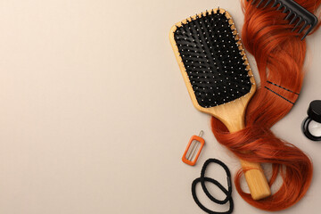 Wooden brush, comb and red hair strand on light background, flat lay. Space for text