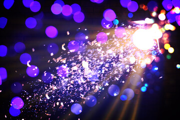 Bright spotlight, beams of light and falling shiny confetti in darkness of night club, bokeh effect