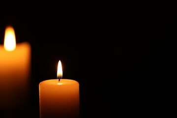 Burning candle on black background, closeup. Space for text