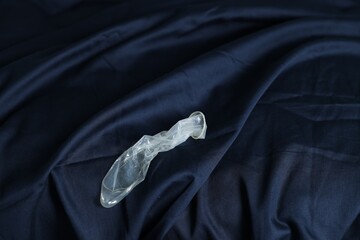 Unrolled condom on bed, above view. Safe sex - obrazy, fototapety, plakaty