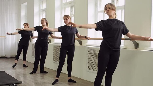 Several women do dance exercises at the ballet barre. Healthy lifestyle concept.