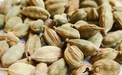 Cardamom, cardamum, cardamomum, or cardamon organic and fresh dried spice seed green pods used as spicy food aromatic flavoring and seasoning condiment or ingredient. Extreme closeup macro side view.