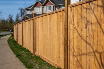 Fototapeta na wymiar Nice new wooden fence around house. Wooden brown fence with green lawn. Street photo