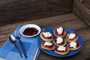 Pikelets Pancakes Battercakes strawberry jam whipped cream blue plate napkin spoon fork rustic...