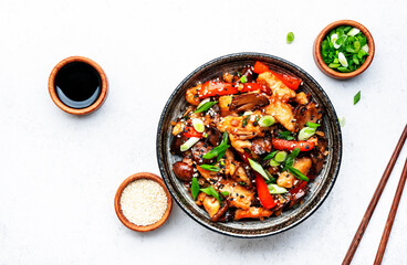 Stir fry chicken fillet, red paprika, mushrooms, green chives and sesame seeds in ceramic bowl Asian cuisine dish. White kitchen table background, top view