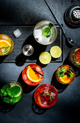 Cocktails set on black bar counter, top view. Mixology concept. Assortment of colorful strong and...