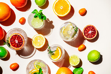 Gin tonic citrus and herb cocktails set, top view. Assortment of summer drinks for cocktail party. Light beige background, bright fruits, hard light, shadow pattern