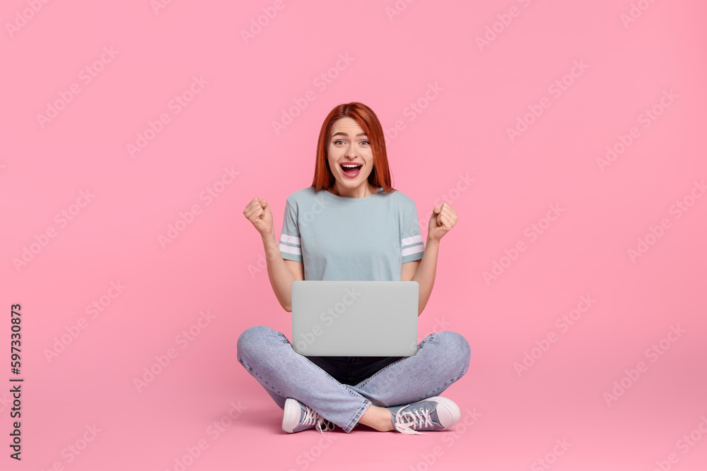 Poster Happy young woman with laptop on pink background