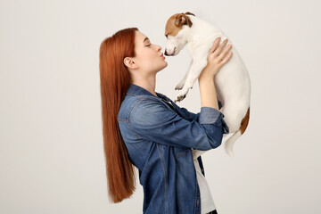 Woman kissing cute Jack Russell Terrier dog on white background. Space for text