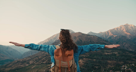 Overjoyed happy woman enjoying beautiful nature mountains around her.Young girl standing on top of...