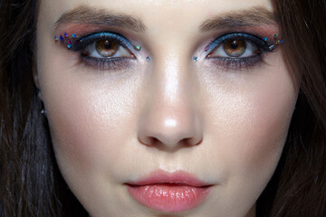 Closeup shot of human woman face. Female with face and eyes beauty makeup with blue eye shadow make up and rhinestones