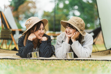 秋冬のキャンプ・アウトドアで友達と遊ぶアジア人女性キャンパー
