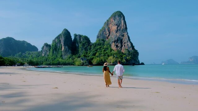 Railay Beach Krabi Thailand, the tropical beach of Railay Krabi, a couple of men and women on the beach, Panoramic view of idyllic Railay Beach in Thailand with a traditional long boat. 