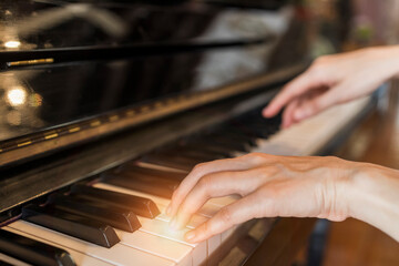 Hands of woman playing grand piano in musical school.Two hand with different level and...