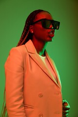 African american woman smile and fashion wearing glasses green background in neon light color mixed light, bright color dancing, futuristic party. Beauty African American woman with pigtails emotions.