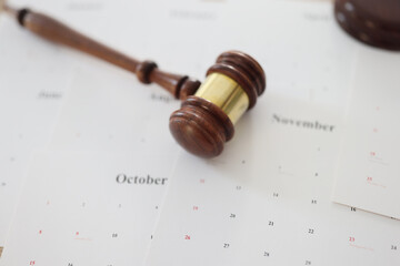 Wooden judge gavel and sound block lie on calendar paper