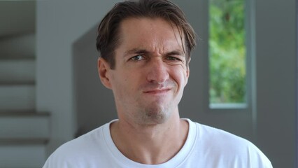 Close-up of confused man peering at the camera in disbelief and making a no gesture shaking his head. The man is ashamed and makes a facepalm, demonstrating disbelief irritation by trouble.