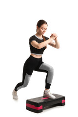 Sporty young woman training with stepper on white background