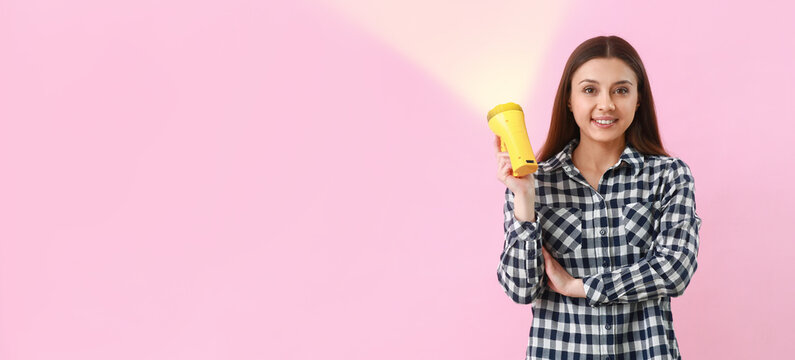 Woman with flashlight on pink background with space for text