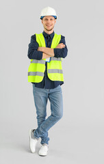 Male worker in vest and hardhat on grey background