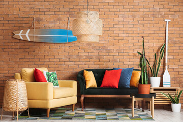 Interior of stylish living room with cozy sofas, cactus and surfboard